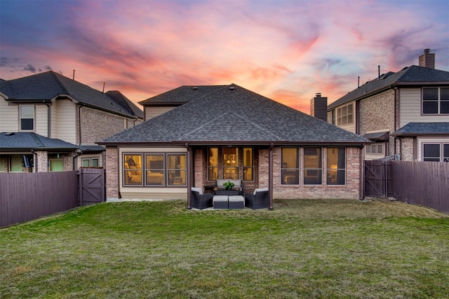 1005 Brendan Dr, Little Elm, TX 75068 - back of house at dusk with a gate, outdoor lounge area, brick siding, and a shingled roof