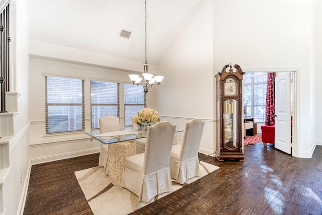 dining space featuring high vaulted ceiling, a notable chandelier, dark wood-style flooring, visible vents, and baseboards