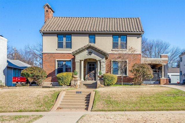 view of front of home with a tiled roof, a chimney, a front yard, and stucco siding