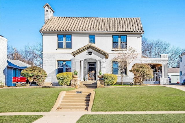 view of front of home with brick siding, a chimney, a front yard, and a tile roof