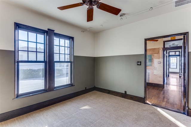 carpeted empty room featuring visible vents, baseboards, and ceiling fan