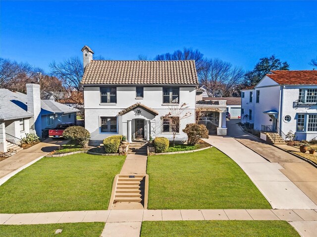 view of front of home featuring a tile roof, a front lawn, and a chimney