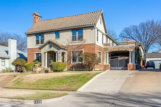 view of front of house featuring brick siding, stucco siding, a tile roof, and a gate