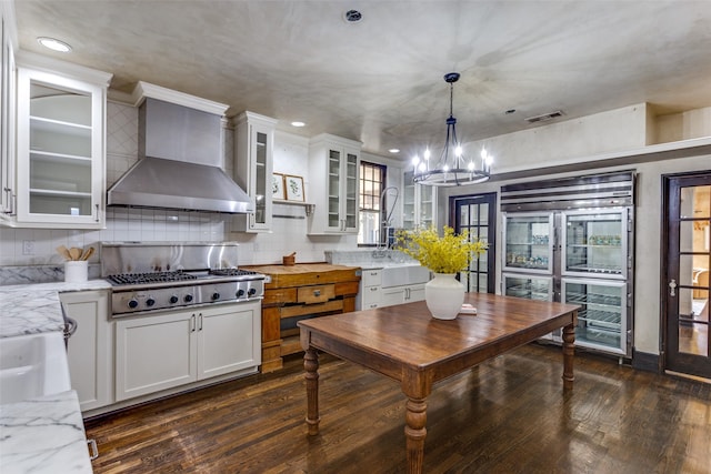 kitchen with visible vents, built in refrigerator, white cabinetry, stainless steel gas stovetop, and wall chimney exhaust hood