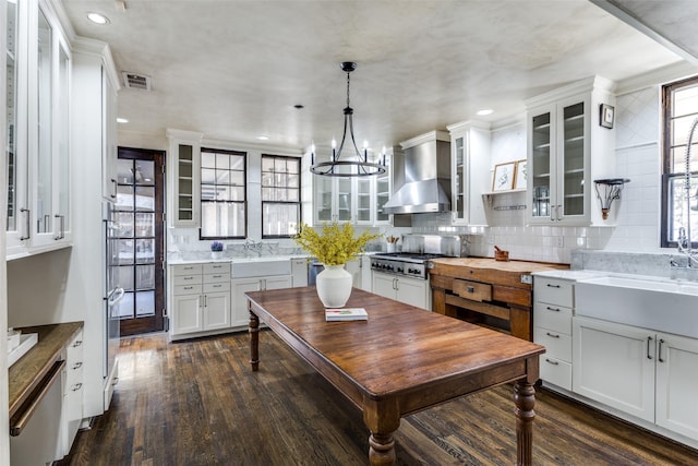 kitchen featuring dark wood-type flooring, wall chimney exhaust hood, visible vents, and a sink