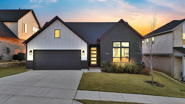 view of front facade with a garage, concrete driveway, a front lawn, and board and batten siding