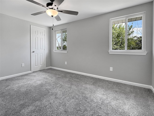 carpeted spare room featuring ceiling fan and baseboards