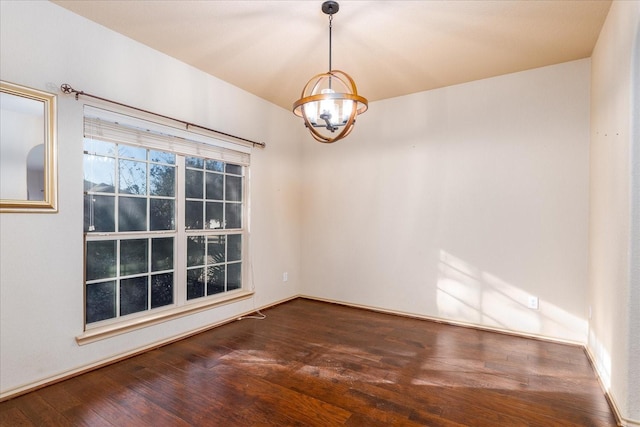 unfurnished room featuring dark wood finished floors and a notable chandelier