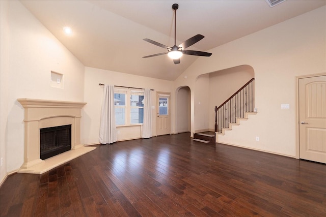 unfurnished living room featuring arched walkways, a fireplace with raised hearth, dark wood finished floors, and stairs