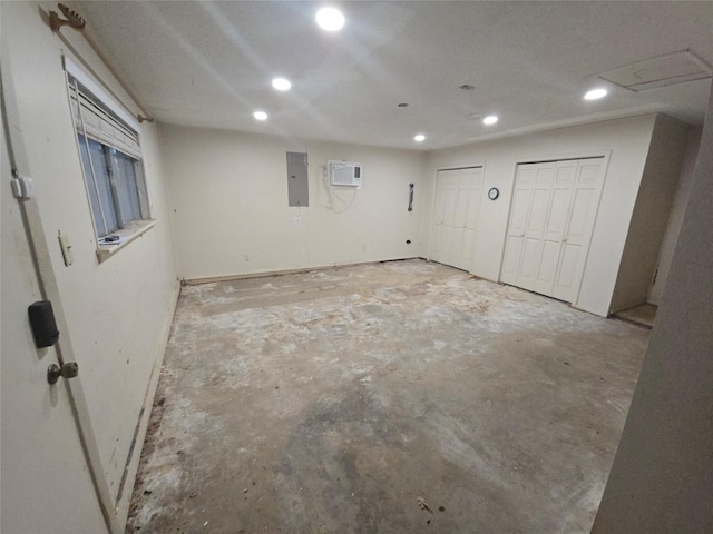 basement featuring an AC wall unit, electric panel, and recessed lighting