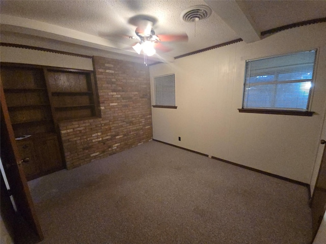 carpeted spare room featuring baseboards, visible vents, brick wall, ceiling fan, and a textured ceiling