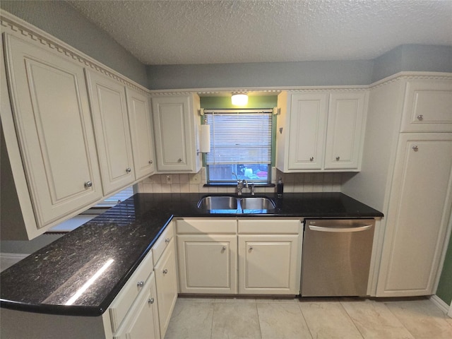 kitchen with a sink, white cabinetry, stainless steel dishwasher, decorative backsplash, and dark stone countertops