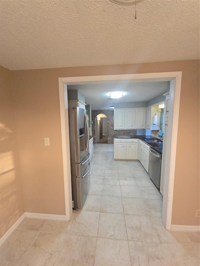 kitchen featuring dark countertops, baseboards, appliances with stainless steel finishes, and white cabinets