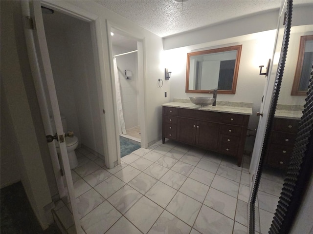 bathroom with a stall shower, toilet, vanity, and a textured ceiling