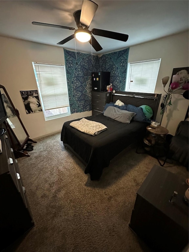 carpeted bedroom with a ceiling fan, multiple windows, and baseboards