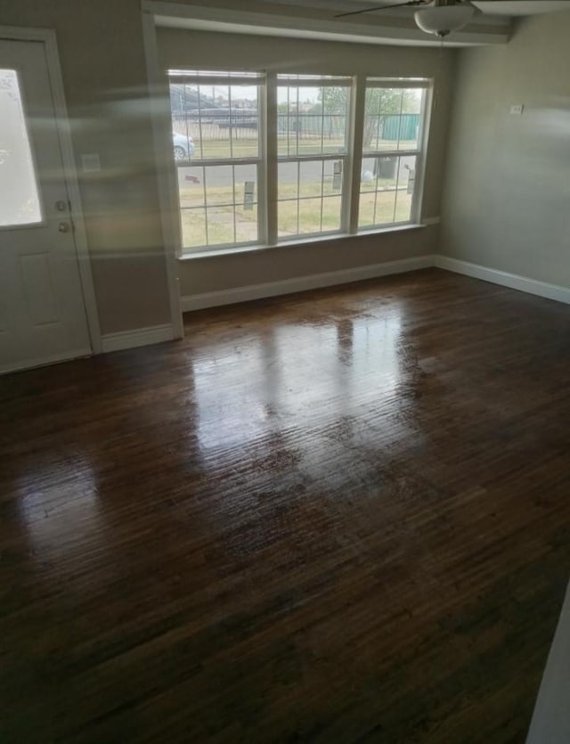 spare room featuring ceiling fan, baseboards, and dark wood finished floors