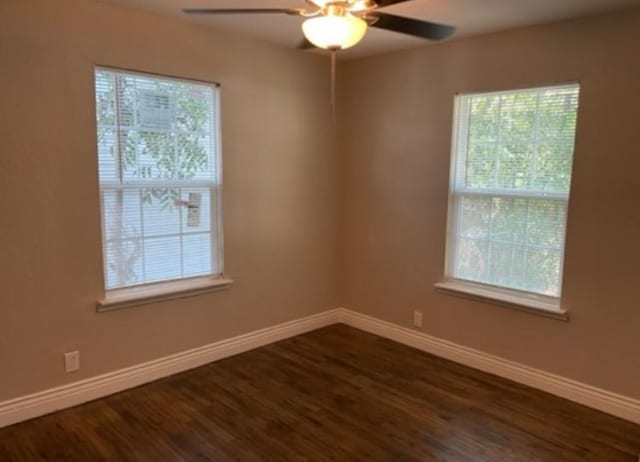 empty room with dark wood-type flooring, baseboards, and a ceiling fan