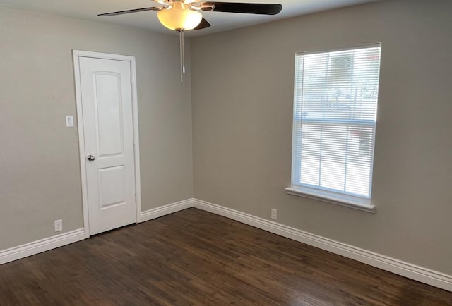 unfurnished room with dark wood-style floors, a ceiling fan, and baseboards