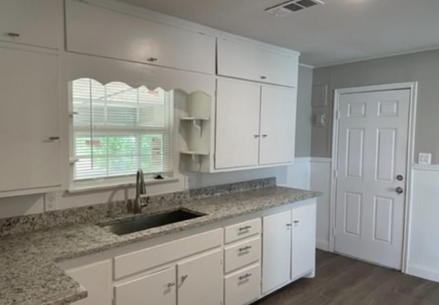 kitchen with a sink, visible vents, white cabinetry, light stone countertops, and open shelves