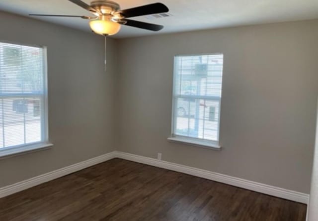 unfurnished room featuring ceiling fan, visible vents, baseboards, and dark wood finished floors