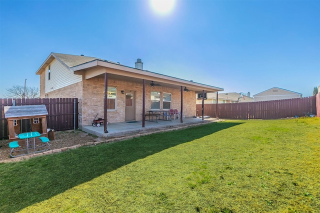 rear view of property featuring a yard, a patio, brick siding, and a fenced backyard