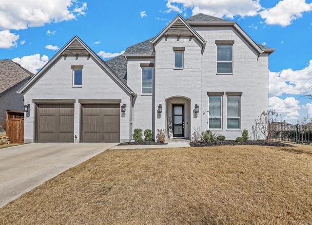 french provincial home with an attached garage, brick siding, fence, concrete driveway, and a front yard