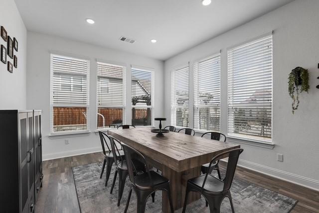 dining space with dark wood-style floors, visible vents, and baseboards