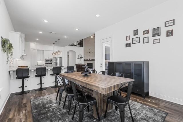 dining room with dark wood-style floors, baseboards, arched walkways, and recessed lighting