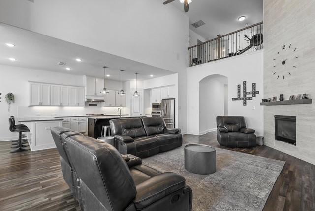 living area with arched walkways, ceiling fan, dark wood-type flooring, a fireplace, and recessed lighting