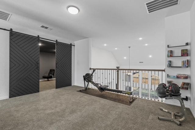 workout room featuring carpet floors, a barn door, and visible vents