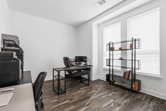 office area with dark wood-type flooring, visible vents, and baseboards