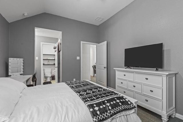 bedroom featuring ensuite bathroom, visible vents, vaulted ceiling, and dark colored carpet