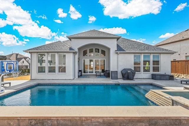 back of property with roof with shingles, stucco siding, a patio area, fence, and an outdoor pool