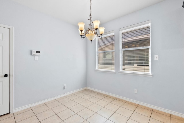 unfurnished room featuring an inviting chandelier, light tile patterned floors, and baseboards