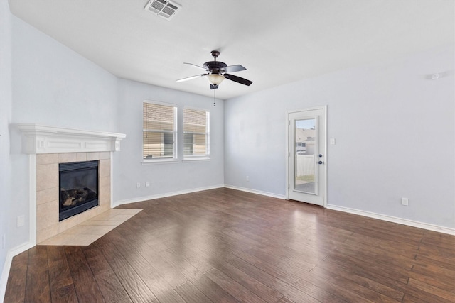 unfurnished living room featuring visible vents, a ceiling fan, wood finished floors, a tile fireplace, and baseboards