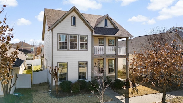 view of front of property featuring a balcony, a shingled roof, a gate, and fence