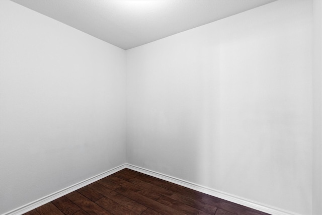 spare room with dark wood-type flooring and baseboards