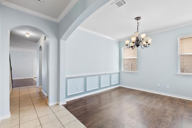 spare room with visible vents, a chandelier, wood finished floors, and ornamental molding