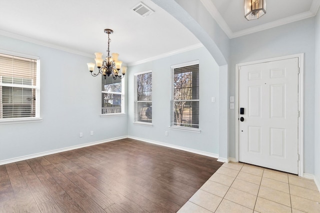 foyer entrance with arched walkways, crown molding, baseboards, and wood finished floors