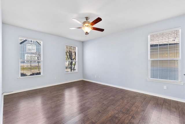 empty room featuring a ceiling fan, dark wood-style flooring, and baseboards