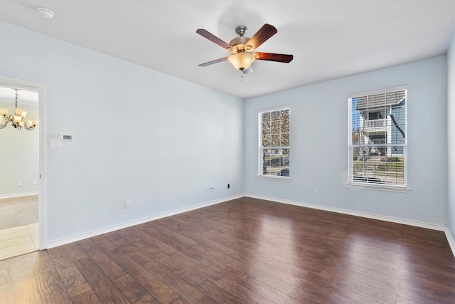 spare room featuring baseboards, wood finished floors, and ceiling fan with notable chandelier