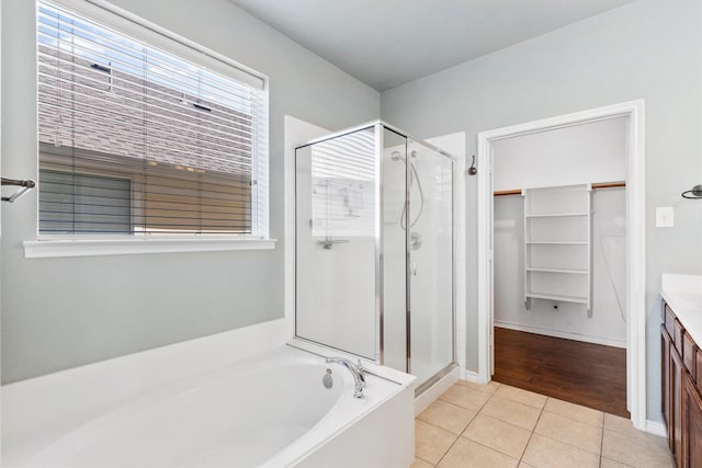 bathroom featuring a stall shower, tile patterned floors, a garden tub, a spacious closet, and vanity