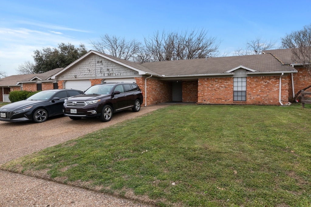 ranch-style house with a front yard, brick siding, driveway, and an attached garage