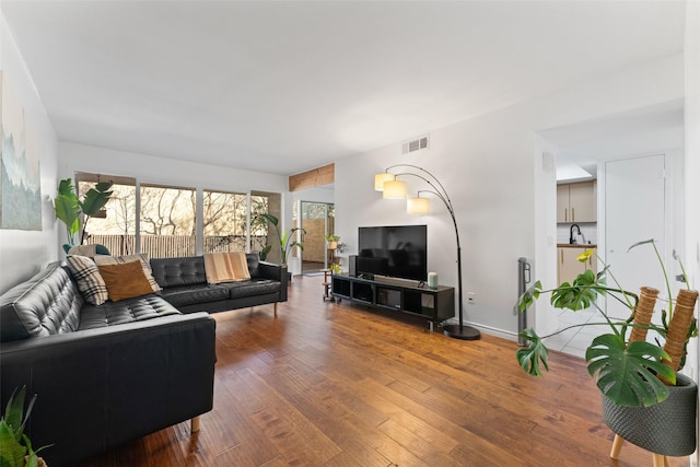 living area with visible vents, baseboards, and wood finished floors