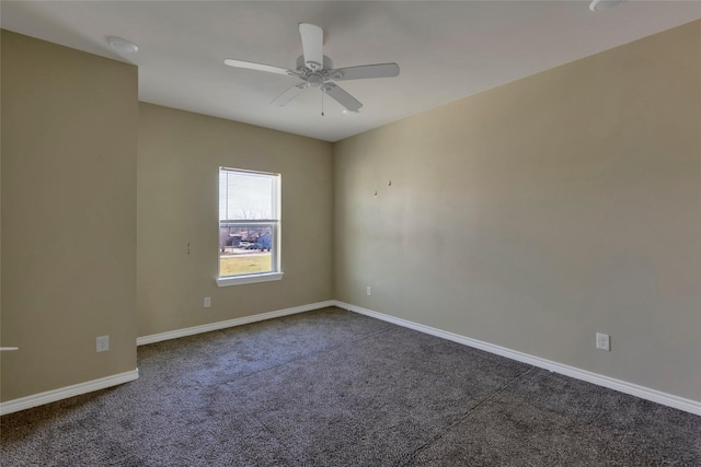 unfurnished room featuring baseboards, dark carpet, and a ceiling fan