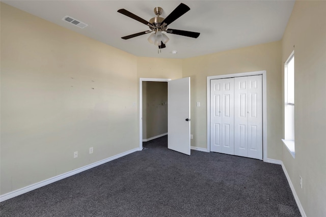unfurnished bedroom with visible vents, dark carpet, baseboards, and multiple windows