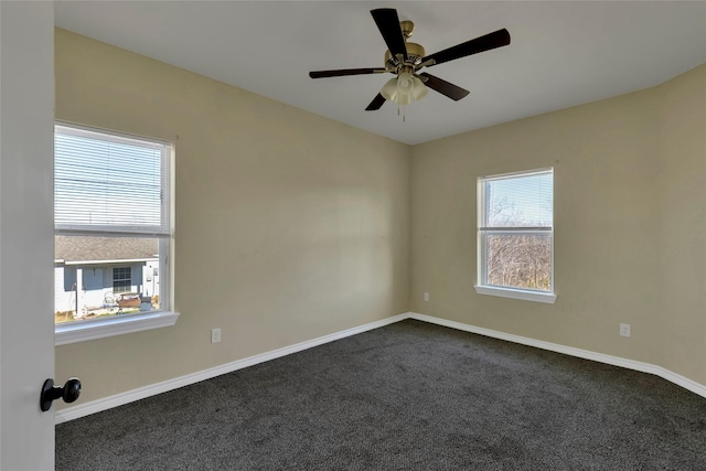 empty room featuring ceiling fan, dark carpet, and baseboards