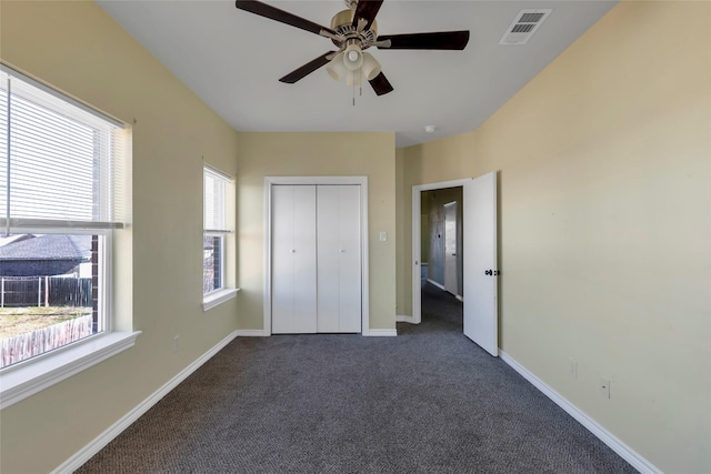 unfurnished bedroom featuring ceiling fan, visible vents, baseboards, a closet, and dark carpet