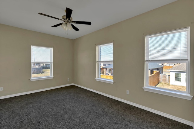 empty room with a ceiling fan, dark carpet, and baseboards
