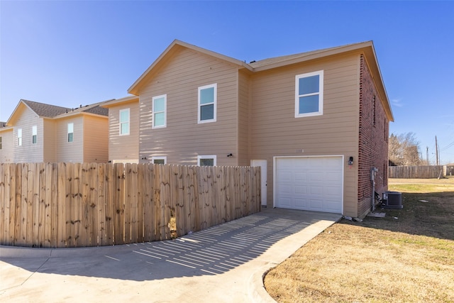 view of side of property featuring a garage, central AC, brick siding, fence, and driveway
